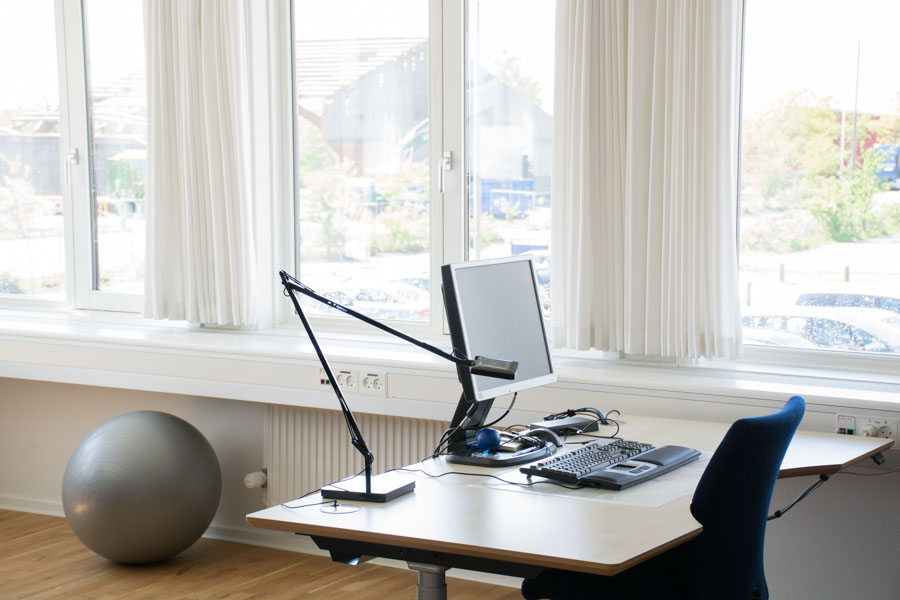 Lyst moderne kontormiljø med klassiske lyse gardiner i vinduet.